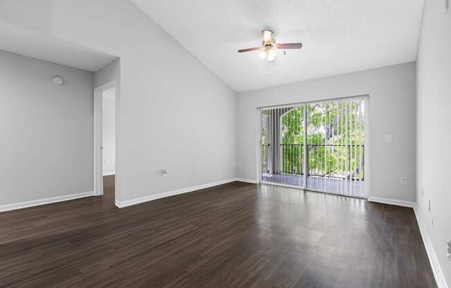 A room with a ceiling fan and sliding glass doors.