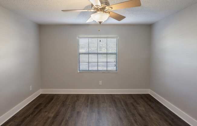 an empty room with wooden floors and a ceiling fan