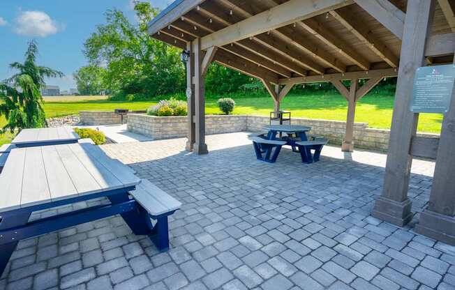 A pavilion with a picnic table and benches is surrounded by a brick patio.