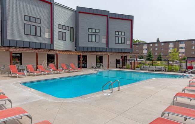 a swimming pool with chaise lounge chairs and a building in the background
