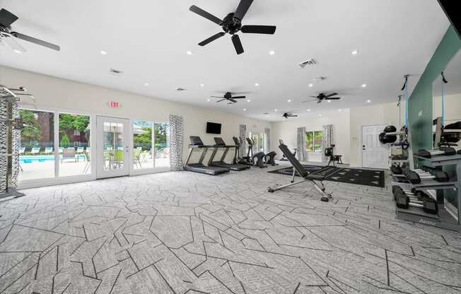 a gym with chairs and a ceiling fan and a pool