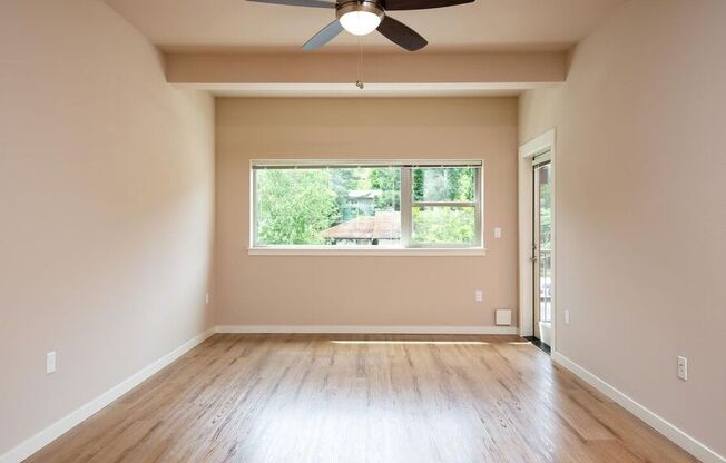 a empty living room with a window and a ceiling fan