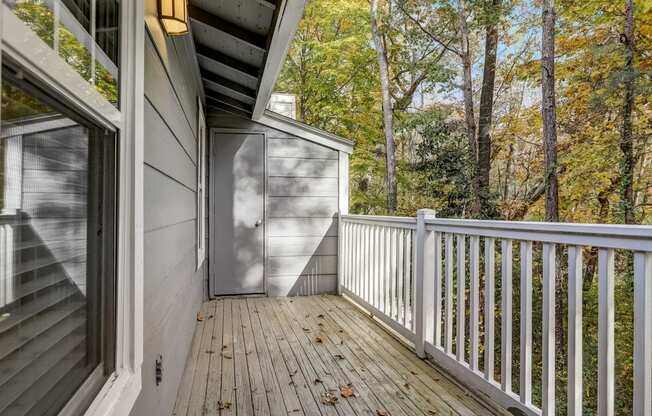 a deck with a view of the woods and a door to a storage closet at Veridian at Sandy Springs