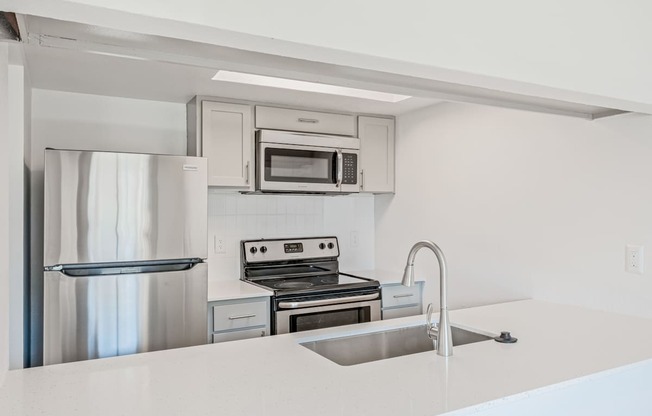 A modern kitchen with stainless steel appliances and white countertops.
