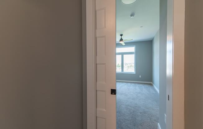 an open door into an empty living room with a ceiling fan