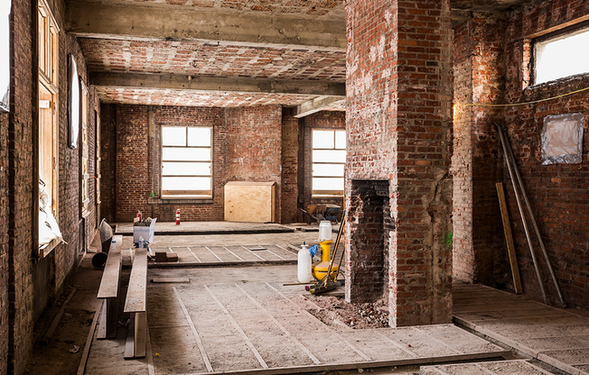 Before: Well-lit room surrounded by windows and adorned in exposed brick during renovation