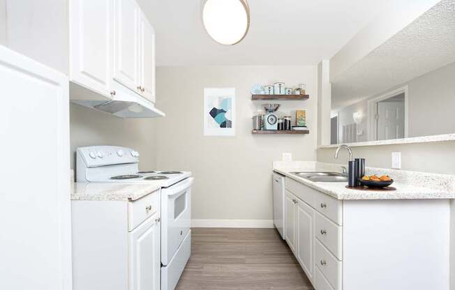 A white kitchen with a stove, oven, and sink.