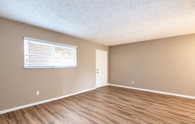 Unfurnished living room with a wide window and wood-look flooring at Waterchase Apartments in Largo, FL.