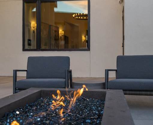 A modern patio with a fire pit and two chairs.