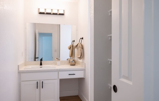 A bathroom with a white vanity and a mirror above it.