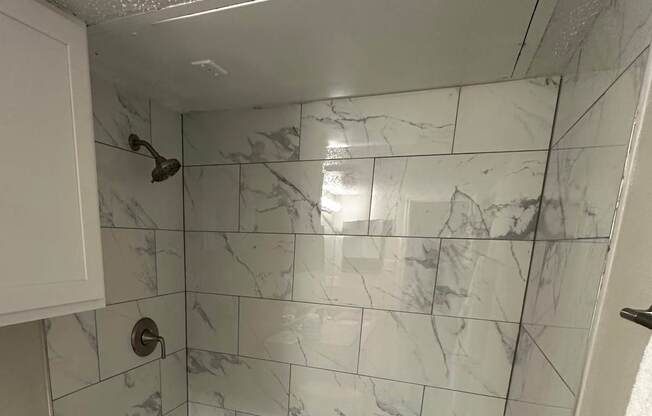 A white toilet sits next to a white bathtub in a bathroom with marble tile flooring.