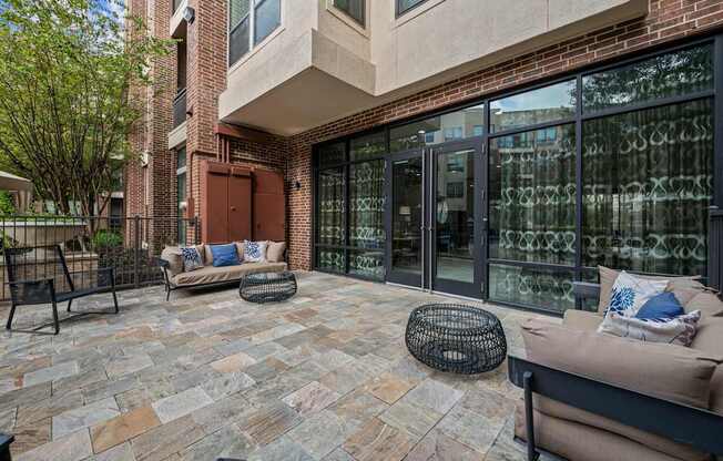 a patio with two couches and chairs in front of a building