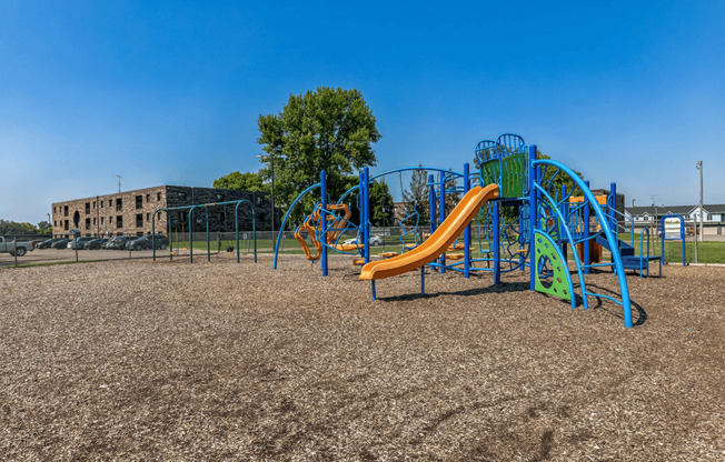 a playground with a yellow and blue slide and a green and blue climbing structure