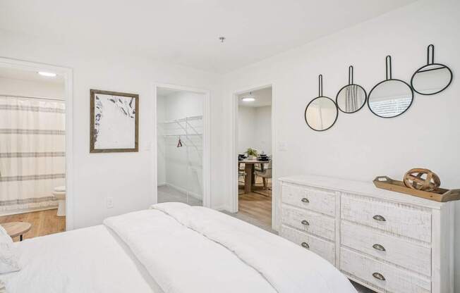 A white bedroom with a large bed and a white dresser.