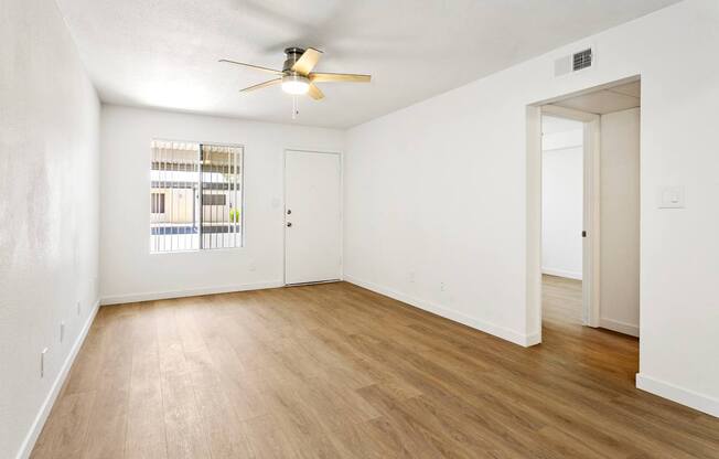 A room with a ceiling fan and a window with blinds.
