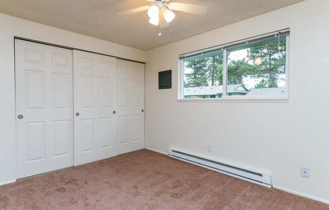 Pinewood Terrace Apartments | Second bedroom with closet doors, window and ceiling fan light.