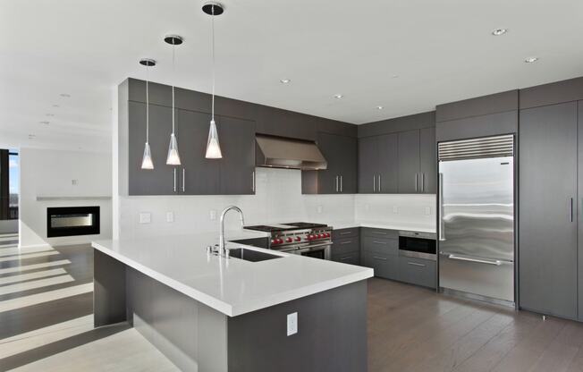 A modern kitchen with dark gray cabinets and white countertops at Bravern, Bellevue, Washington