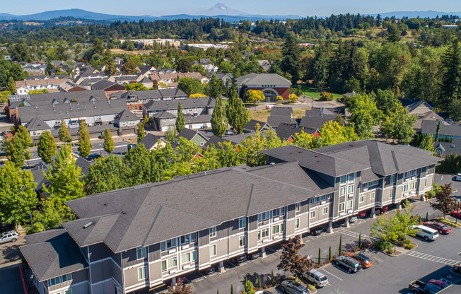 an aerial view of a building surrounded by parking lot and trees