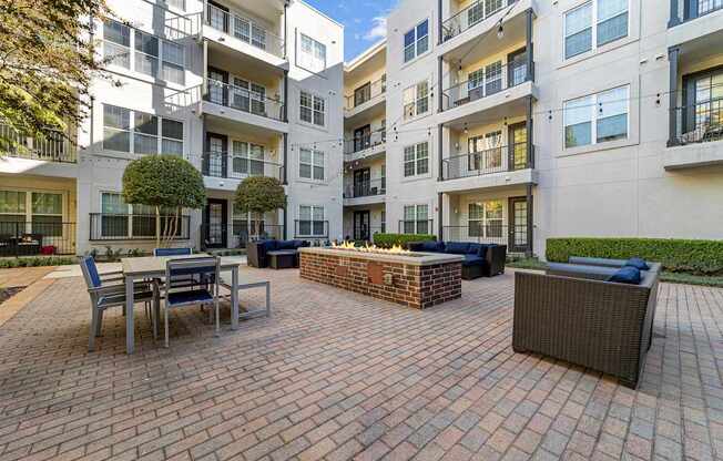 a brick patio with a fire pit in front of an apartment building