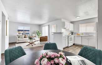 a living room and kitchen with a table with flowers