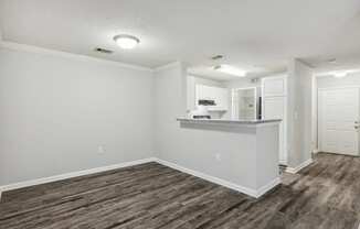 the living room and kitchen of an apartment with wood flooring