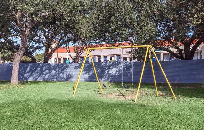 a yellow swing set in a playground with trees