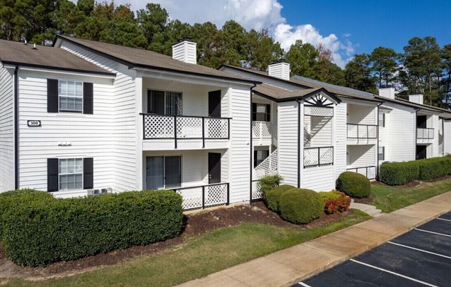 an apartment building with white siding and a sidewalk