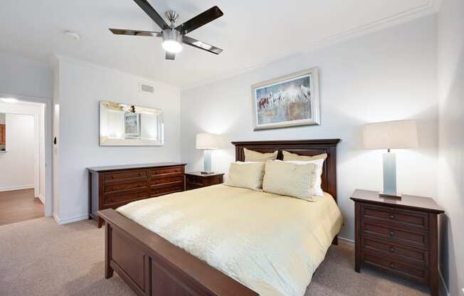 a bedroom with a bed and two dressers and a ceiling fan