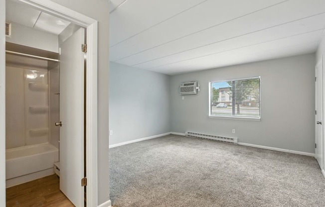 A room with a carpeted floor and a window showing a building outside.