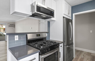 Kitchen with blue tile backsplash and stainless steel Stove, Oven, and fixtures.