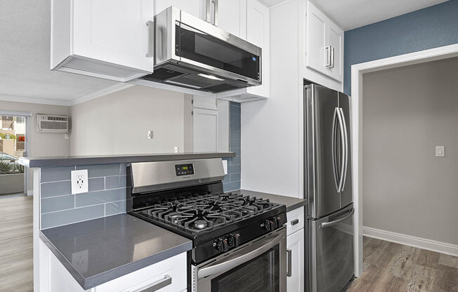 Kitchen with blue tile backsplash and stainless steel Stove, Oven, and fixtures.