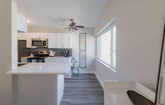 a kitchen with white cabinets and a large window and a white counter top