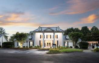 a white house with a parking lot and a sunset in the sky