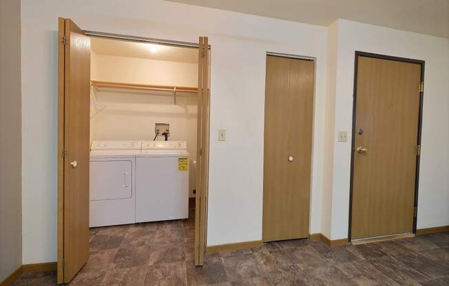 a laundry room with a washer and dryer and a door. Fargo, ND Kennedy Apartments