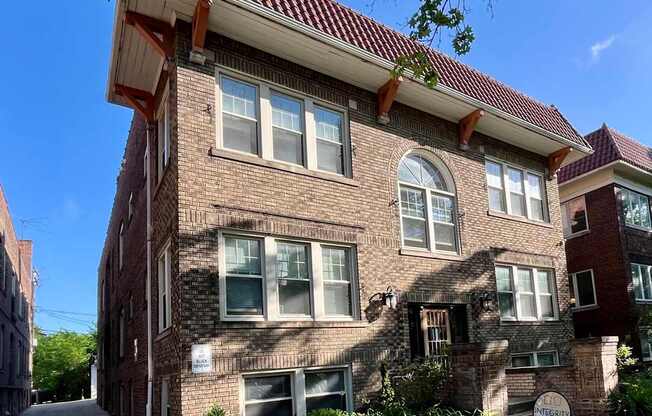 A brick building with a sign in front that says "For Sale".