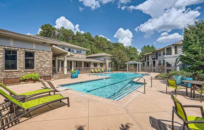 A sunny day at a poolside with green lounge chairs.