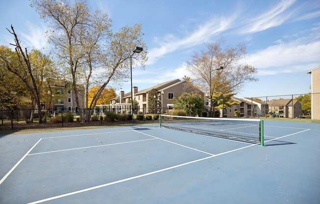 A tennis court surrounded by trees and buildings.