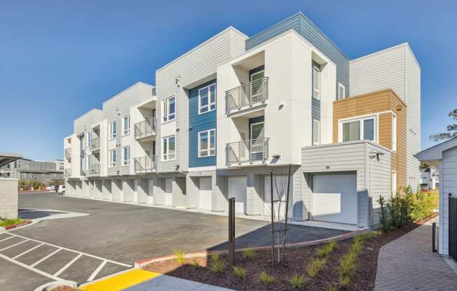 a row of modern apartments with balconies and a parking lot