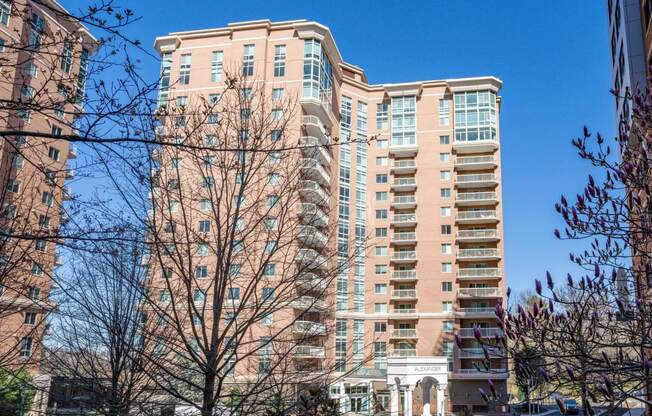 a large apartment building in a city with trees in the foreground