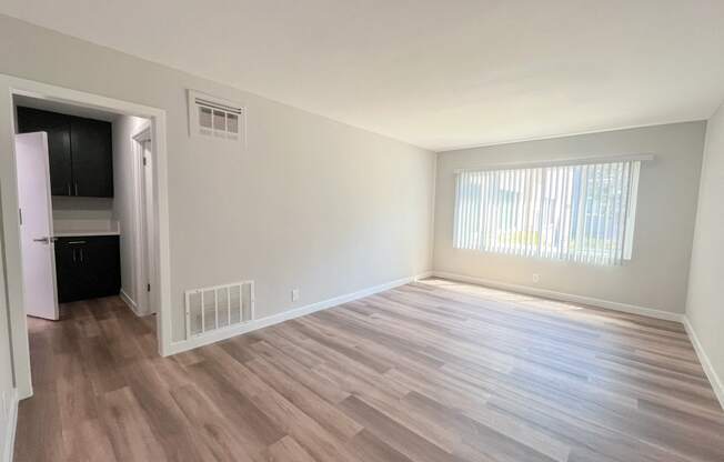 an empty living room with wood flooring and a window