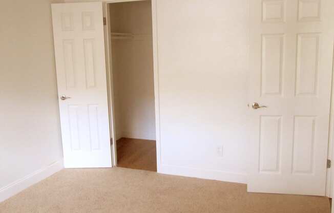 a room with two doors and a carpeted floor and a door to a closet