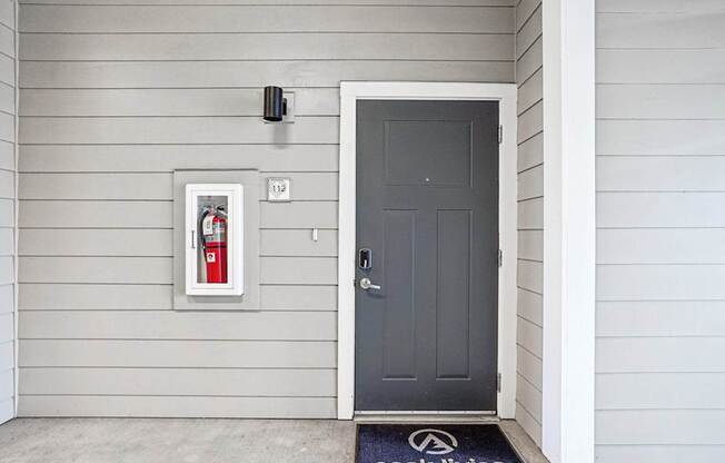 A grey door with a black mat that says Peak Living on it. at Connect at First Creek Apartments, Denver