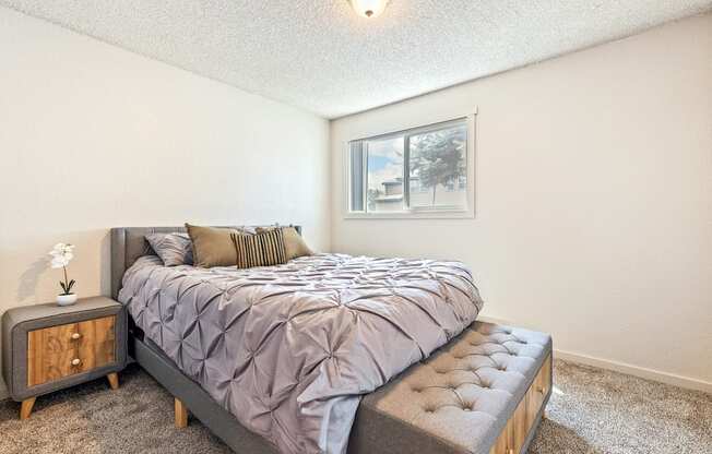 A bedroom with a bed, nightstand, and window at Wildflower, Kennewick, WA 99336.