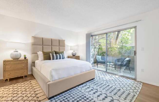 a bedroom with a large bed and a sliding glass door overlooking a private patio