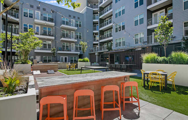 A patio with a table and chairs in front of apartment buildings.