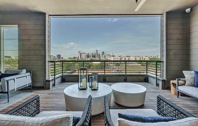 A balcony with a table and chairs overlooking a city skyline.