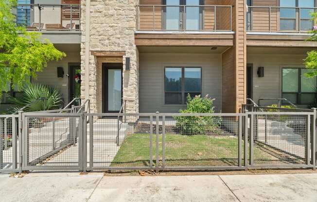A modern two-story apartment building with a metal fence in front.