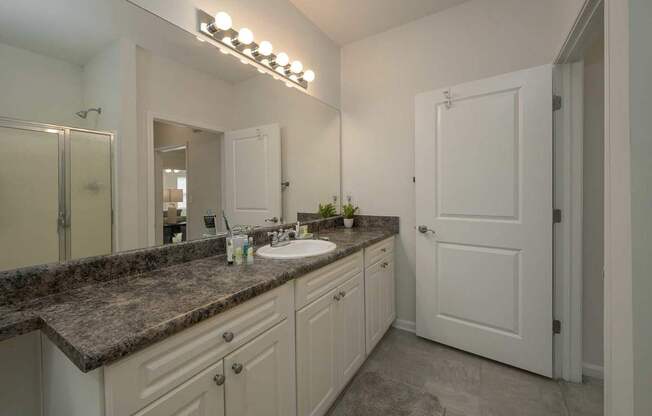 A bathroom with a sink, mirror, and a door.