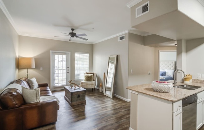 a living room with a couch and a kitchen and a ceiling fan
