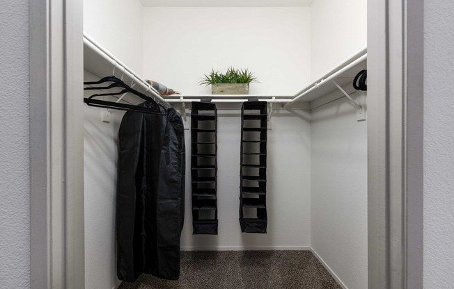 a walk in closet with robes and a plant in it